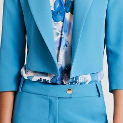 Giacca corta modello boxy realizzata in tessuto tecnico. La giacca ha le maniche a 3/4 e la fodera monogram sur-ton e revers a lancia. 
Il capo può essere utilizzato sia come classica giacca, sia come coprispalle da abbinare ad abiti e tute. Il capo è interamente realizzato in Italia. 
La modella è alta 1,77 e indossa una taglia S.